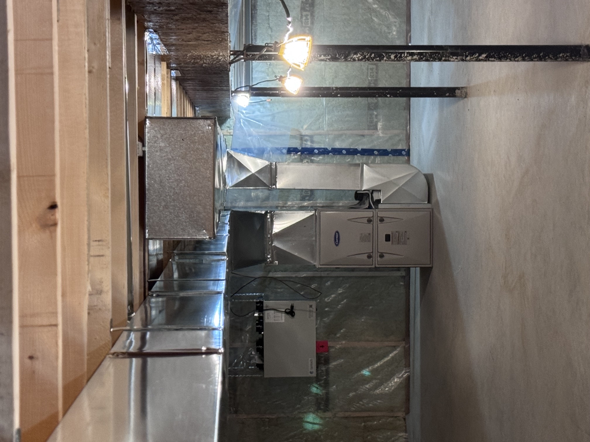 Completed installation with a Carrier furnace and rectangular metal ductwork routed beneath the basement joists