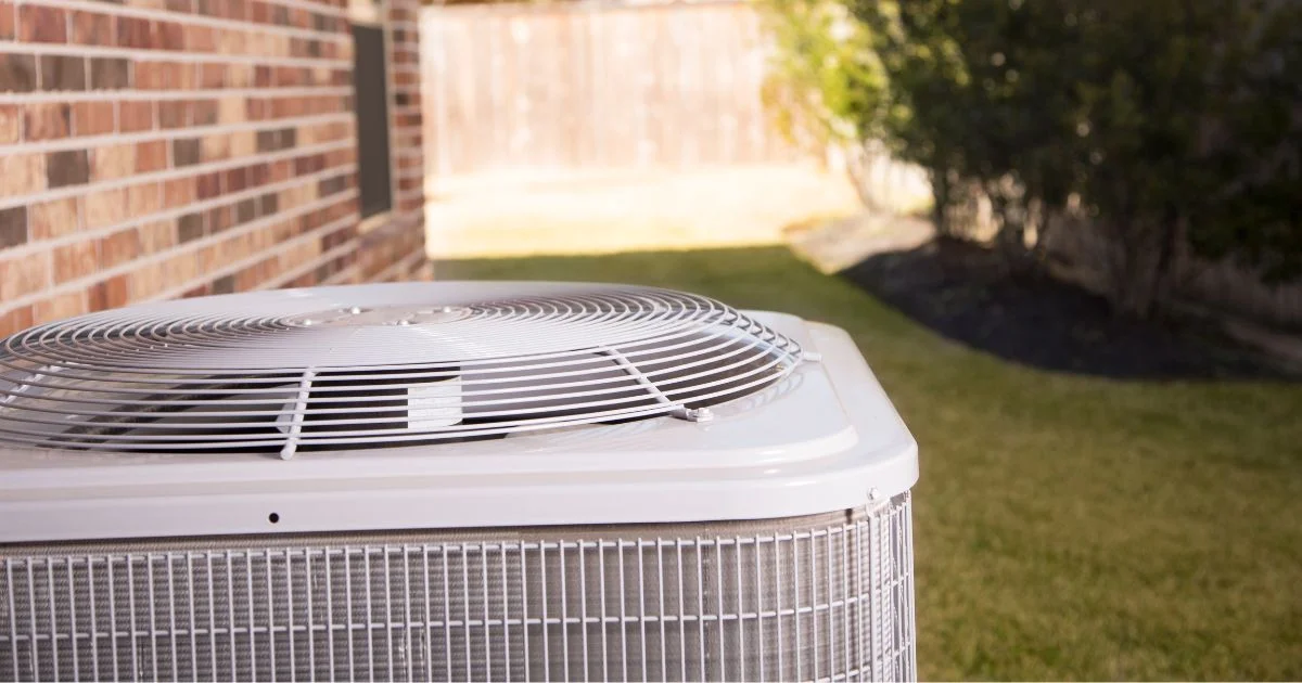 Outdoor central air conditioning condenser unit beside a home