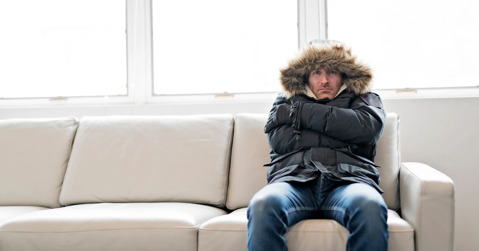 Man wearing winter coat indoors due to lack of home heating