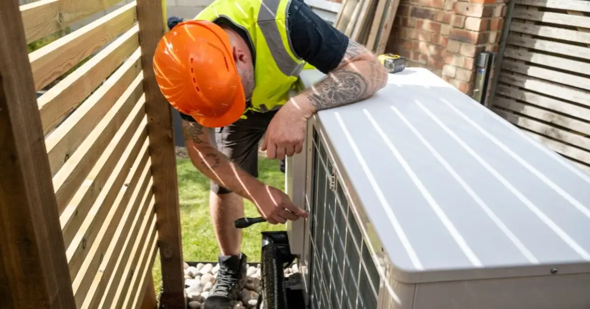 HVAC technician servicing residential outdoor heat pump unit